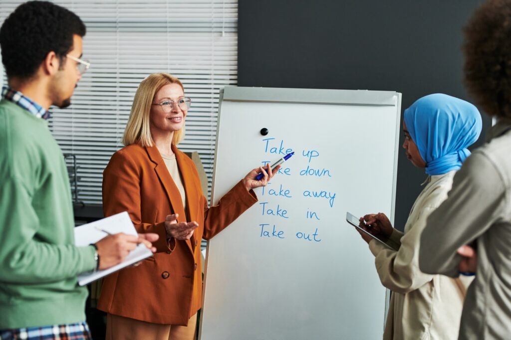 Confident mature teacher of English language pointing at whiteboard